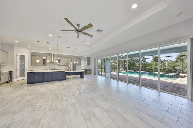 kitchen featuring visible vents, decorative backsplash, wall chimney range hood, light countertops, and gray cabinets