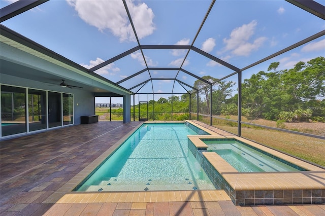 view of swimming pool with a ceiling fan, glass enclosure, a patio area, and a pool with connected hot tub