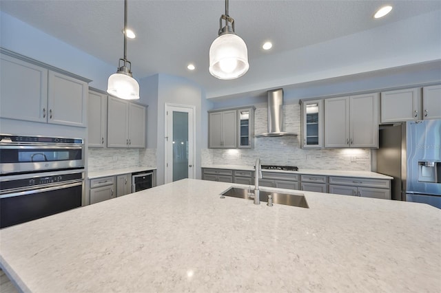 kitchen featuring wine cooler, wall chimney exhaust hood, a sink, backsplash, and gray cabinetry