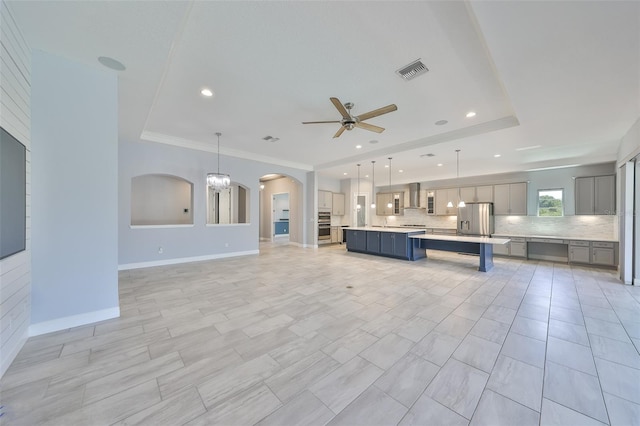 kitchen with ceiling fan, gray cabinets, backsplash, visible vents, and wall chimney exhaust hood