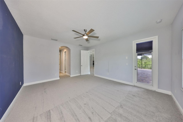 carpeted empty room with visible vents, a ceiling fan, baseboards, and arched walkways