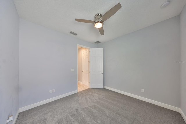 empty room featuring carpet floors, ceiling fan, baseboards, and visible vents