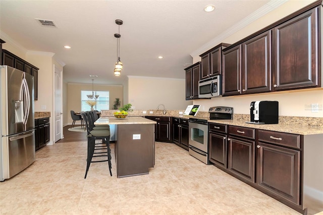 kitchen with appliances with stainless steel finishes, crown molding, a kitchen breakfast bar, decorative light fixtures, and recessed lighting