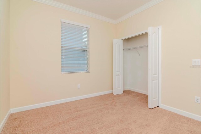 unfurnished bedroom with crown molding, light carpet, baseboards, and a closet