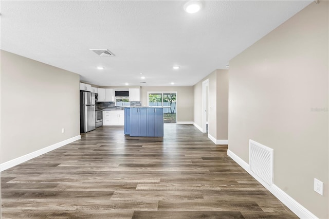 kitchen with visible vents, freestanding refrigerator, a kitchen island, and white cabinets