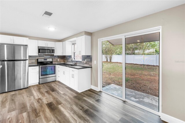 kitchen with decorative backsplash, visible vents, dark countertops, appliances with stainless steel finishes, and white cabinets