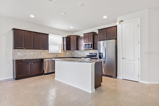 9309 Tradewater Oaks Ct, Riverview, FL 33578 - kitchen featuring appliances with stainless steel finishes, a sink, decorative backsplash, dark brown cabinetry, and light stone countertops