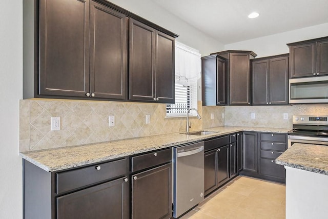 9309 Tradewater Oaks Ct, Riverview, FL 33578 - kitchen with stainless steel appliances, a sink, light stone countertops, dark brown cabinetry, and decorative backsplash