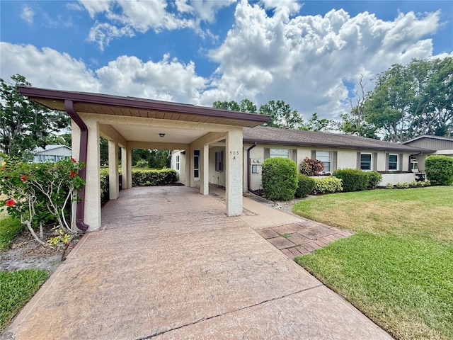 view of front facade featuring stucco siding, driveway, a front yard, and a carport