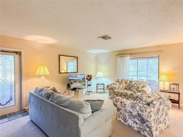 living area with light carpet, a textured ceiling, and visible vents