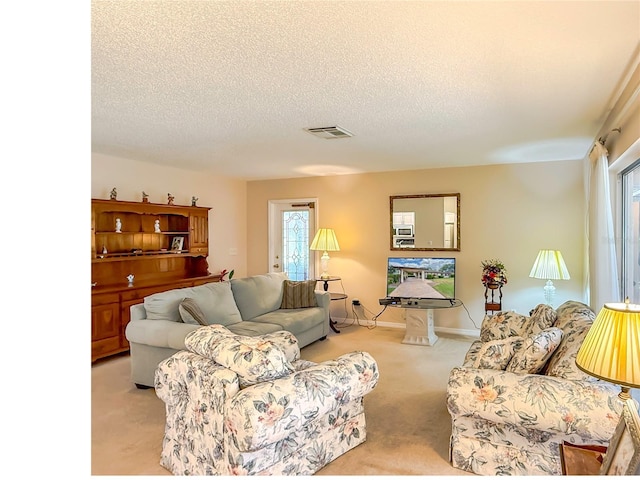living area with visible vents, a textured ceiling, and light colored carpet