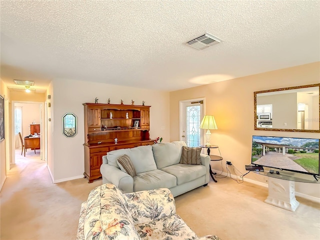 living room featuring baseboards, light carpet, a textured ceiling, and visible vents