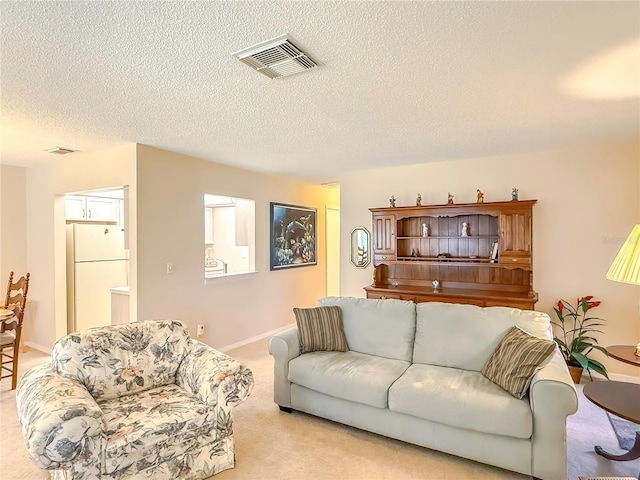 living area featuring visible vents, a textured ceiling, baseboards, and light colored carpet