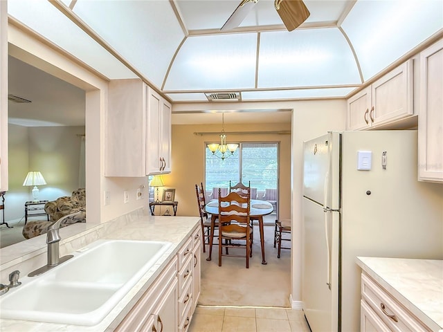 kitchen featuring light colored carpet, hanging light fixtures, a sink, light countertops, and light tile patterned floors