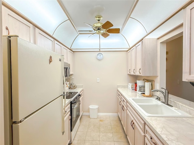 kitchen featuring freestanding refrigerator, ceiling fan, electric stove, stainless steel microwave, and a sink