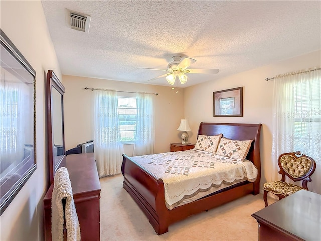 bedroom with visible vents, a textured ceiling, and light carpet