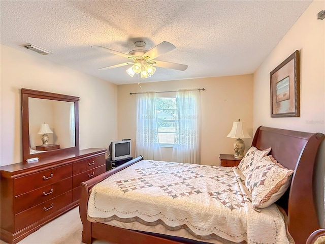 bedroom with a ceiling fan, a textured ceiling, visible vents, and light colored carpet
