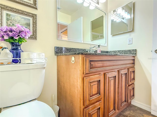 half bathroom featuring toilet, baseboards, and vanity