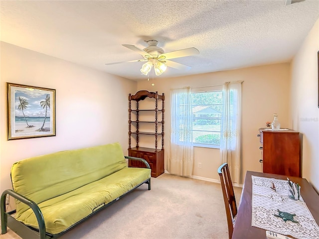 office area featuring a ceiling fan, a textured ceiling, light carpet, and baseboards
