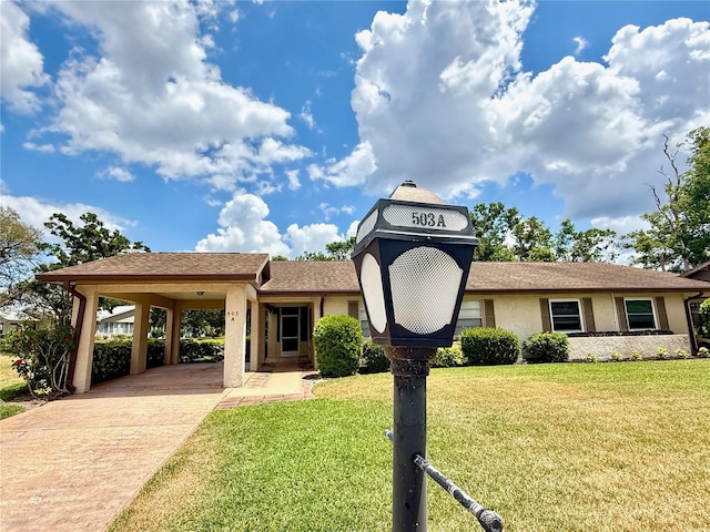 view of front of property with concrete driveway, stucco siding, a front yard, and a carport