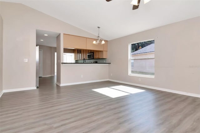 8561 Deer Chase Dr, Riverview, FL 33578 - unfurnished living room with ceiling fan with notable chandelier, wood finished floors, recessed lighting, vaulted ceiling, and baseboards