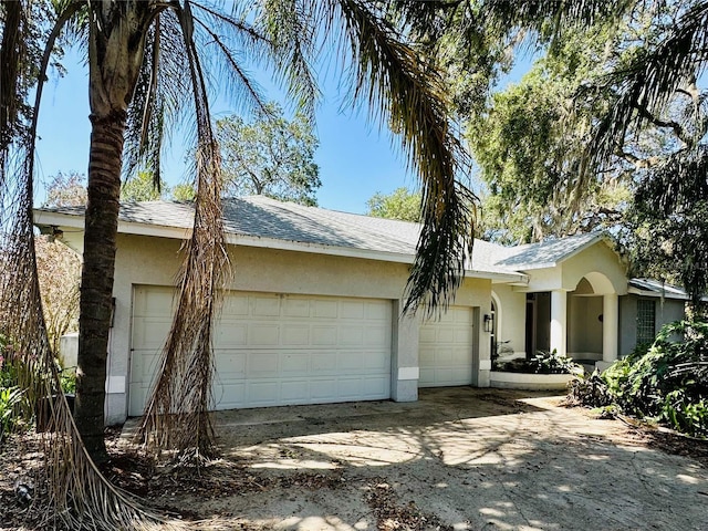 ranch-style home with stucco siding, an attached garage, and driveway