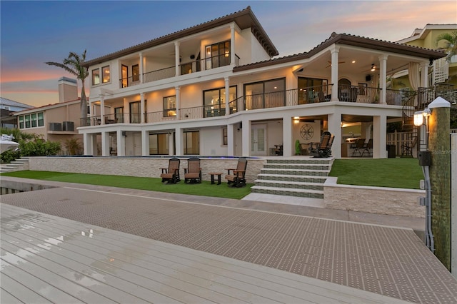 5939 Bayview Cir S, Gulfport, FL 33707 - back of property at dusk with a tiled roof, a patio area, stucco siding, and a balcony