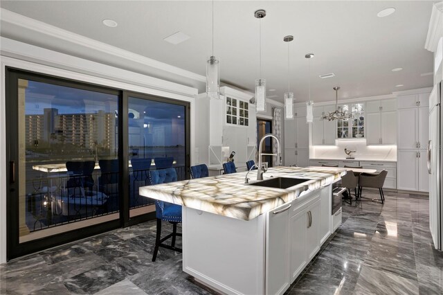 5939 Bayview Cir S, Gulfport, FL 33707 - kitchen with a kitchen island with sink, white cabinetry, a sink, and marble finish floor