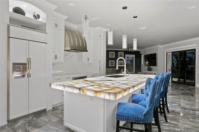 5939 Bayview Cir S, Gulfport, FL 33707 - kitchen with wall chimney range hood, a sink, wooden counters, a center island with sink, and paneled fridge