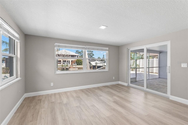 13704 Evelane Dr, Hudson, FL 34667 - spare room featuring light wood-style flooring, healthy amount of natural light, a textured ceiling, and baseboards
