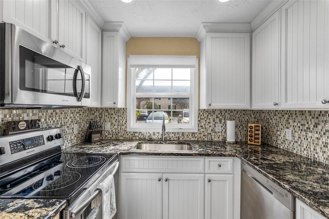 kitchen featuring a sink, appliances with stainless steel finishes, decorative backsplash, and white cabinetry