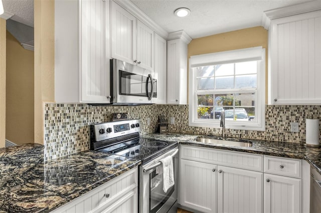 kitchen with white cabinets, stainless steel appliances, a sink, and tasteful backsplash