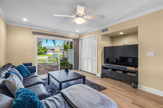 living area with visible vents, a textured ceiling, baseboards, and light wood-type flooring