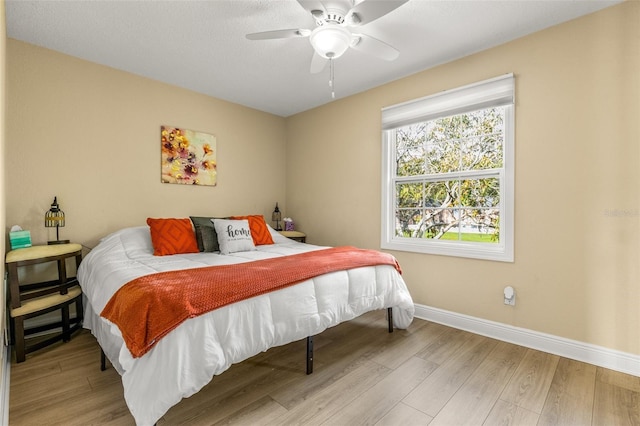 bedroom with a ceiling fan, baseboards, and wood finished floors