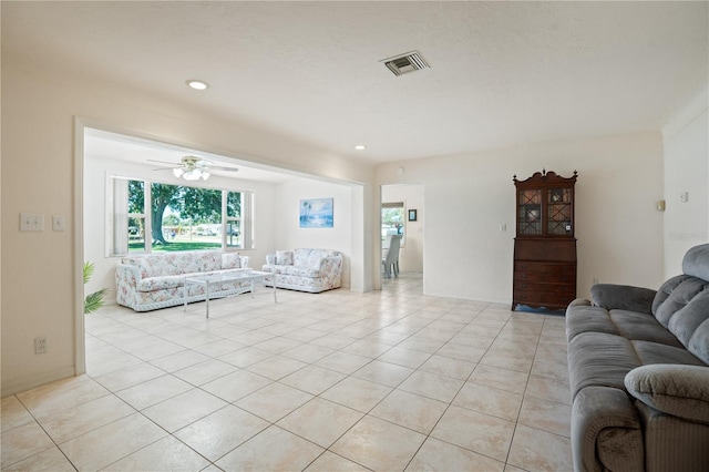 living room with ceiling fan, light tile patterned flooring, and visible vents