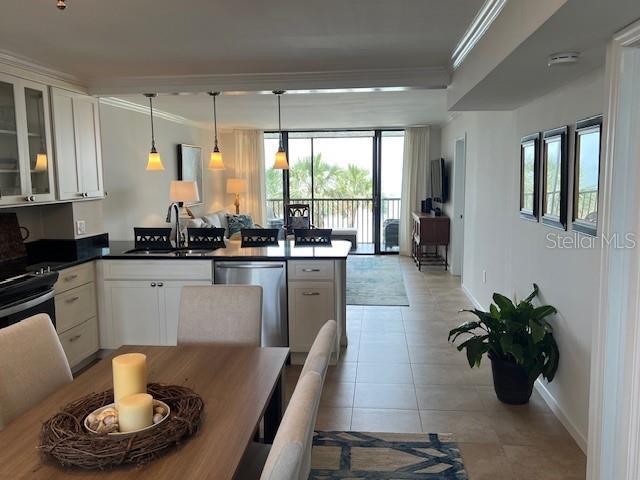18304 Gulf Blvd Unit 309, Redington Shores, FL 33708 - kitchen featuring crown molding, a peninsula, baseboards, stainless steel dishwasher, and dark countertops