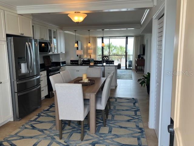 18304 Gulf Blvd Unit 309, Redington Shores, FL 33708 - kitchen with stainless steel appliances, a peninsula, crown molding, dark countertops, and glass insert cabinets