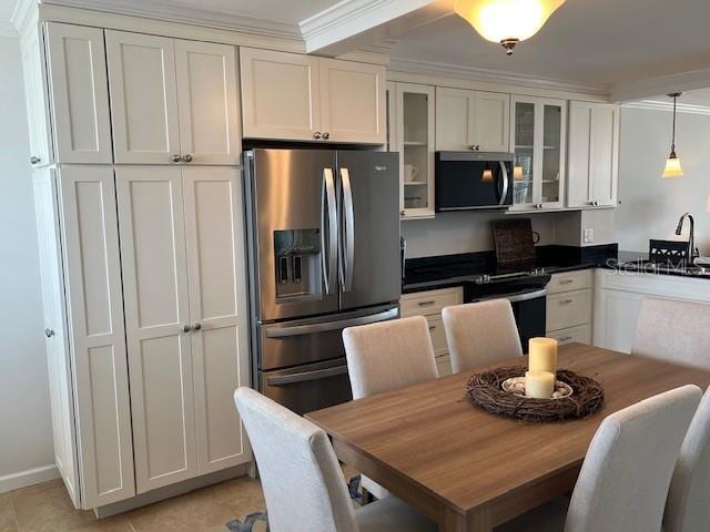 18304 Gulf Blvd Unit 309, Redington Shores, FL 33708 - kitchen featuring appliances with stainless steel finishes, crown molding, glass insert cabinets, pendant lighting, and dark countertops