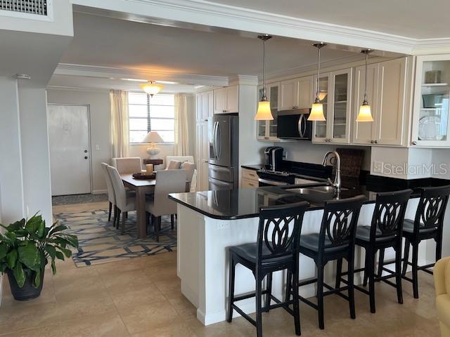 18304 Gulf Blvd Unit 309, Redington Shores, FL 33708 - kitchen featuring appliances with stainless steel finishes, a sink, a peninsula, a kitchen bar, and crown molding