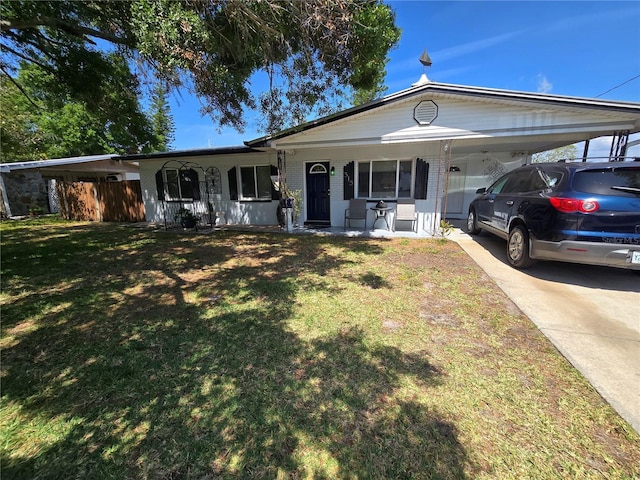 ranch-style house featuring an attached carport, concrete driveway, a front lawn, and covered porch