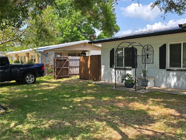 view of property exterior featuring brick siding, fence, and a yard