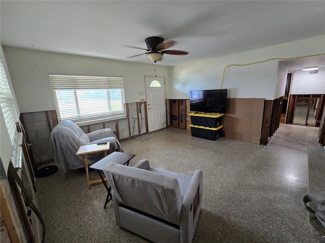 living room with ceiling fan and wainscoting
