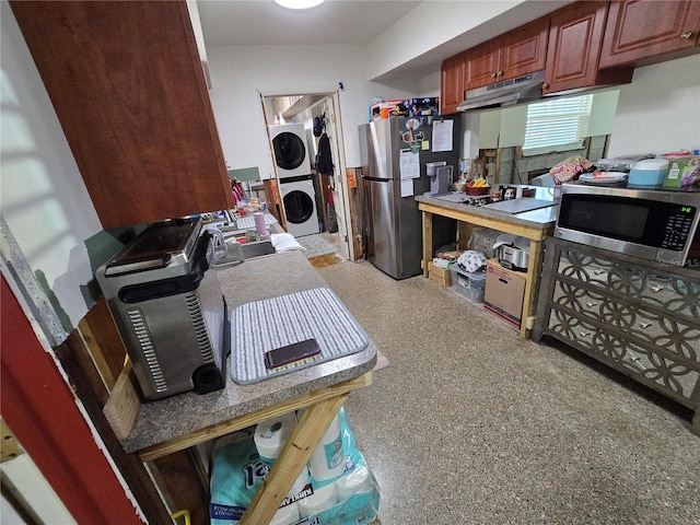 kitchen featuring light speckled floor, appliances with stainless steel finishes, stacked washer / drying machine, and under cabinet range hood
