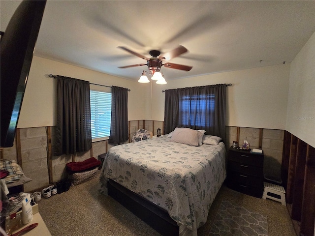 bedroom with dark colored carpet, a ceiling fan, a baseboard radiator, and a wainscoted wall