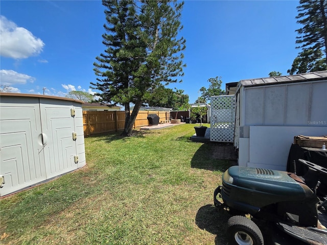 view of yard featuring an outbuilding, a fenced backyard, and a storage unit