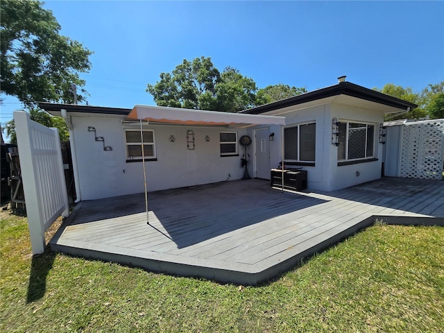 back of property with fence, a wooden deck, and stucco siding