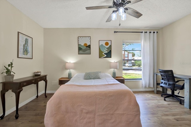 bedroom featuring a textured ceiling, baseboards, and wood finished floors