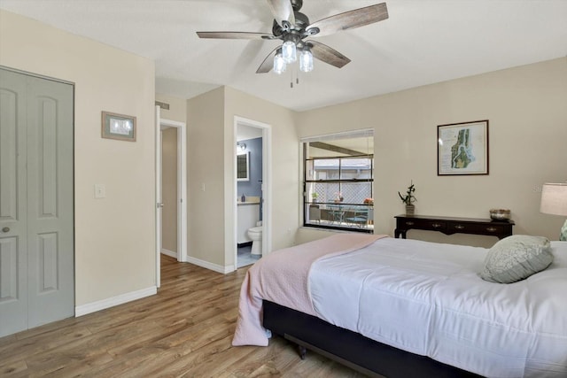 bedroom with baseboards, ceiling fan, wood finished floors, and ensuite bath