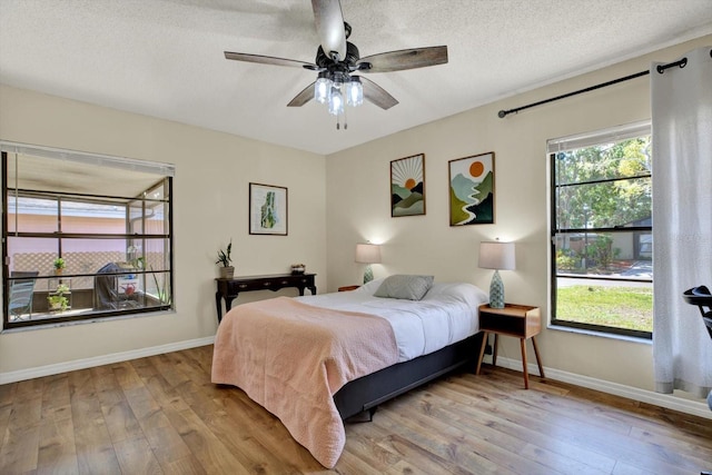 bedroom with baseboards, wood-type flooring, and a textured ceiling