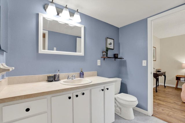 bathroom with vanity, baseboards, wood finished floors, and toilet